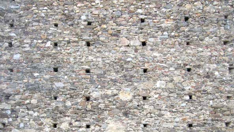 Image of a stone wall with scaffolding holes